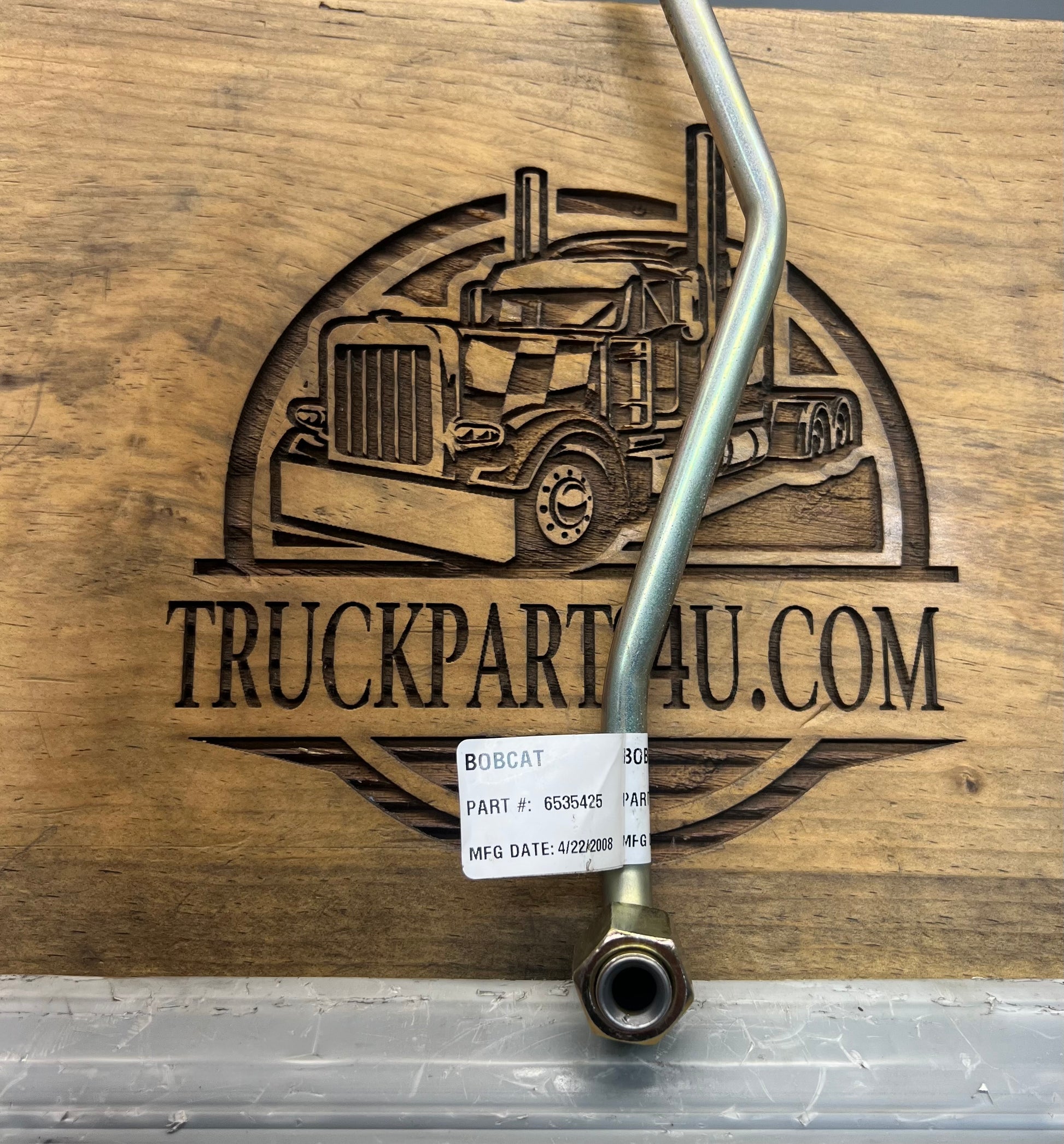 Close-up of Bobcat steel tube assembly label showing OEM part number 6535425 and manufacturing date