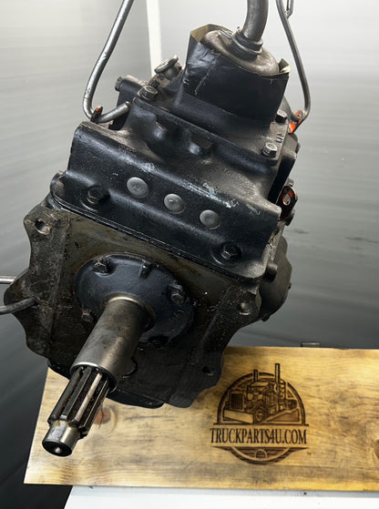Brand new NOS Turner-Spicer T5A-3278 (T5A-300 series) 5-speed overdrive transmission front view hanging for display, showing top-mounted shifter tower and linkage, protected splined input shaft, and pristine black cast iron case